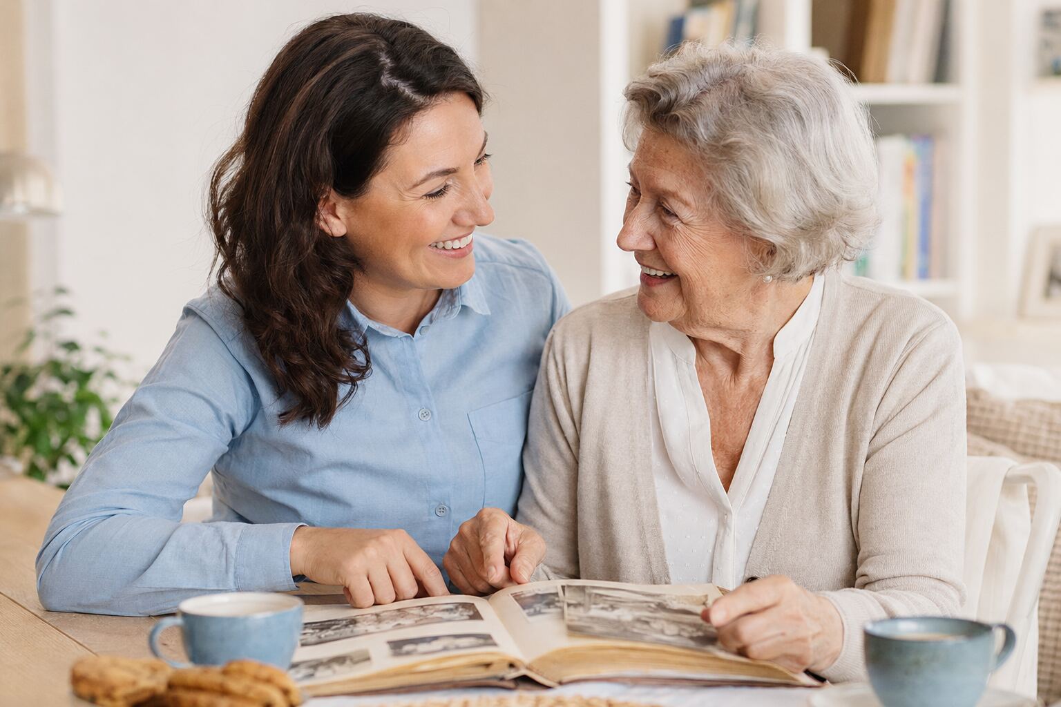 Alltagshelferin und Seniorin verbringen gemeinsam Zeit bei Gesprächen und einem Fotoalbum